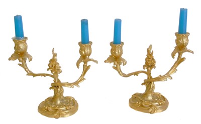 Lot 190 - A Pair of late 19th century gilded metal Rococo design two branch table candlesticks.