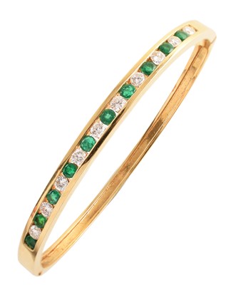 Lot 31 - Diamond and emerald set 18ct yellow gold bangle