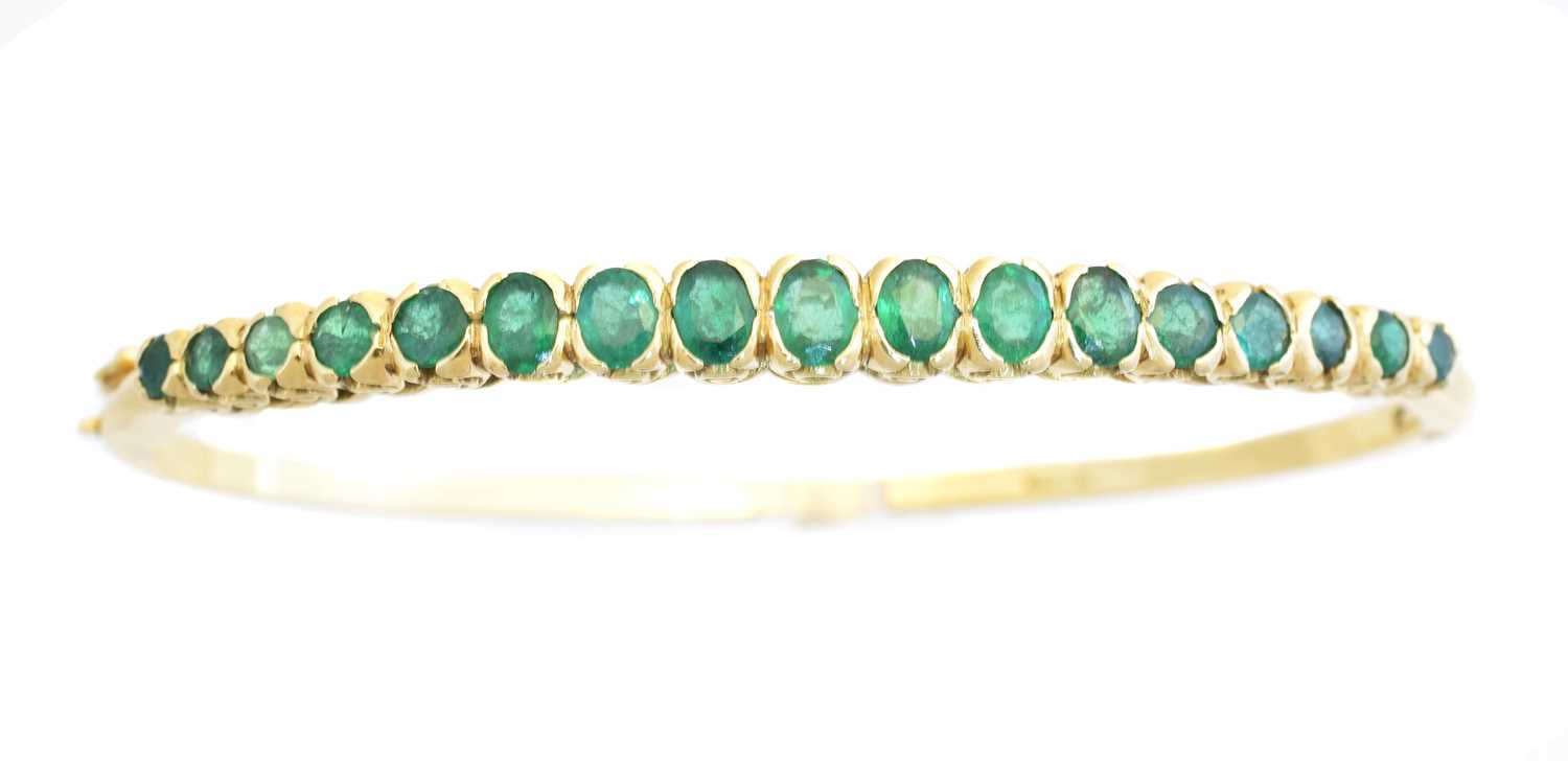 Lot 13 - An 18ct gold emerald hinged bangle