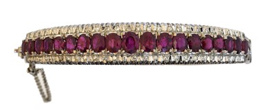 Lot 66 - An 18ct gold ruby and diamond hinged bangle