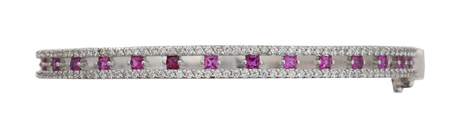 Lot 26 - A 9ct gold ruby and diamond hinged bangle.