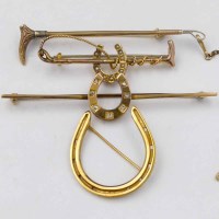 Lot 343 - Four gold horse shoe / crop brooches.