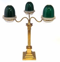 Lot 36 - Clarkes three branch Cricklite brass table top library lamp with three press glass pans supporting green and white cased shades.