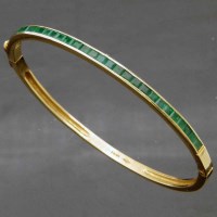 Lot 259 - 595 gold and emerald hinged bangle (1 stone broken)