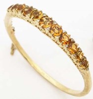 Lot 353 - 9ct gold hinged bangle, the half hoop set with