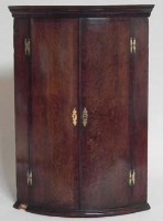 Lot 568 - George III oak bow fronted hanging corner cupboard