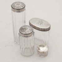 Lot 406 - Four glass toiletry jars with silver tops.