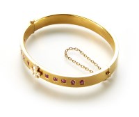 Lot 188 - An Edwardian 15ct gold ruby and seed pearl set hinged bangle